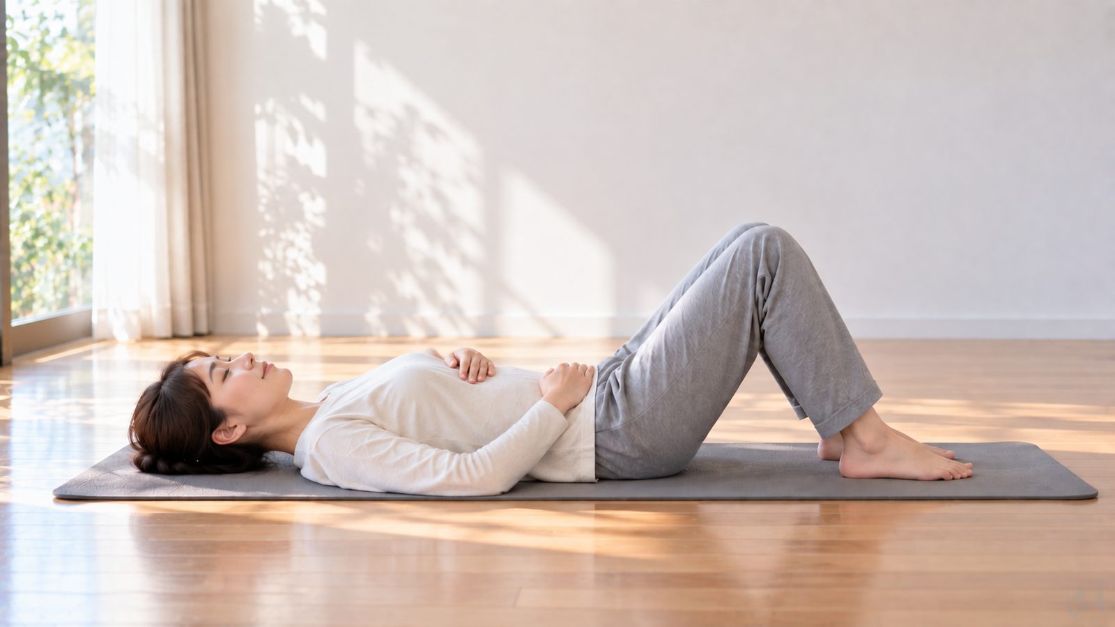 仰向けで膝を立て、肋骨とおなかに手を当てて呼吸を整える姿勢